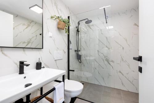 ein weißes Bad mit einer Dusche und einem WC in der Unterkunft Villa Marica Tiny House in Krk city centre in Krk