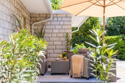 a patio with wicker furniture and an umbrella at Villa Marica Tiny House in Krk city centre in Krk
