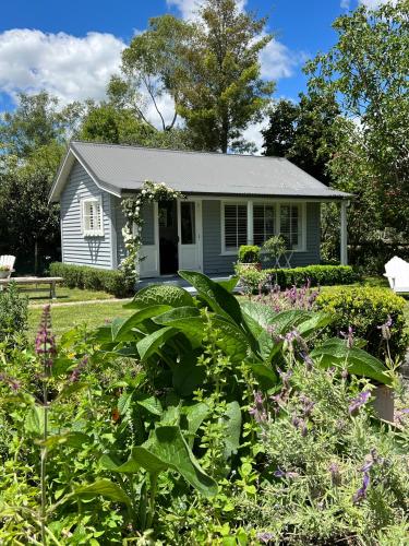 a small house with a garden in front of it at Gardeners' Cottage in Hamilton