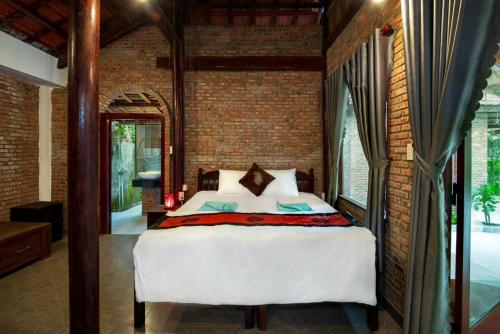 a bedroom with a bed in a brick wall at An Vien Coffee & Villa in Hoi An