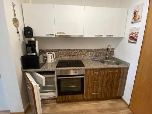 een kleine keuken met een fornuis en een wastafel bij Apartment mit Seeblick in Strobl
