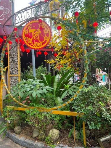 a garden with red lanterns and flowers in front of a building at An Vien Coffee & Villa in Hoi An