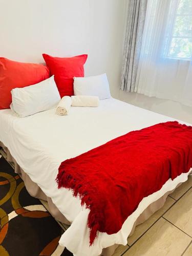 a large bed with a red blanket on it at Frere Hill Guesthouse in Durban