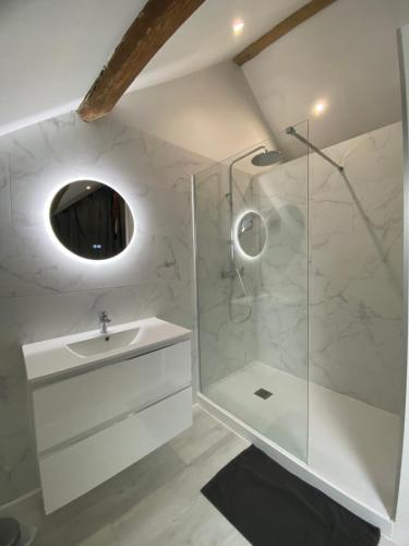 a white bathroom with a sink and a shower at Les maisons des Frangines 