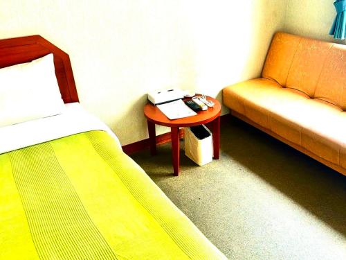 石垣島にあるホテルハッピーホリデー石垣島 のベッドルーム1室(ベッド1台、ソファ、テーブル付)