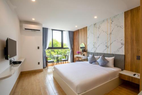 a bedroom with a large white bed and a television at FIRST Studio Hotel in Da Nang