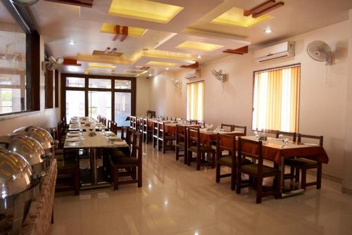 comedor con mesas y sillas de madera en Hotel Sai Sangam, en Shirdi