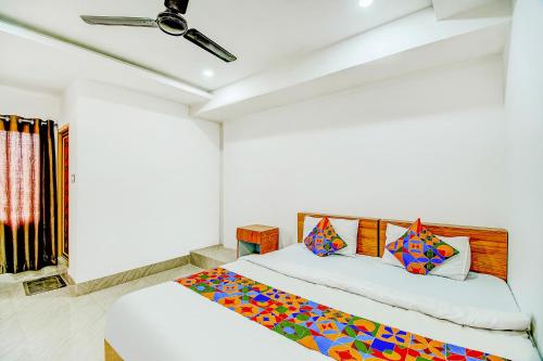 グワーハーティーにあるFabExpress Lakhiの白いベッドルーム(カラフルな枕付きのベッド1台付)