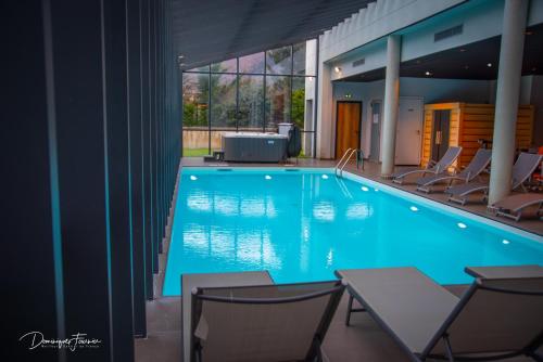 uma grande piscina azul com cadeiras num edifício em LE CASTEL D'ALTI em Luchon