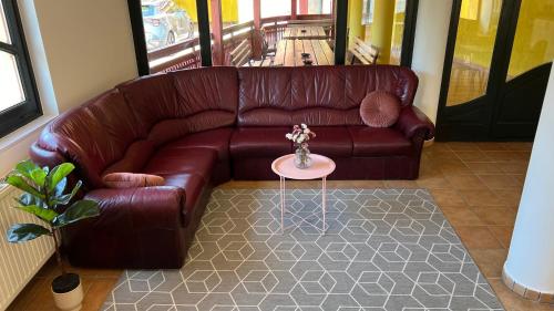 a brown leather couch in a living room with a table at Nussbaum Panzió in Keszthely