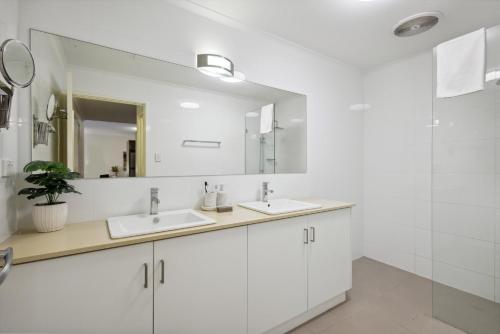 a white bathroom with two sinks and a mirror at Urban Serenity 2 Bedroom Apt with Stunning Views in Perth
