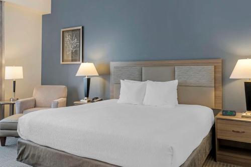 a bedroom with a large white bed and a chair at Best Western Plus Peppertree Nampa Civic Center Inn in Nampa
