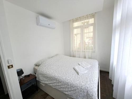 a white bedroom with a bed and a window at Suite Chanzy 69 in Reims