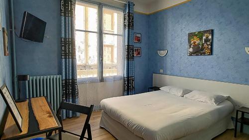 - une chambre avec un lit aux murs bleus et une fenêtre dans l'établissement Trianon, à Vichy