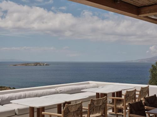 a patio with tables and chairs and the ocean at Boheme Mykonos Town - Small Luxury Hotels of the World in Mikonos