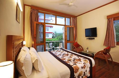 a bedroom with a bed and a window and a television at De Vivendi Resorts, Manali with 35000 Sqft Open Lawn in Manāli