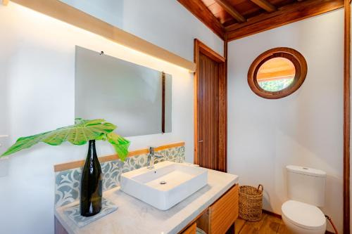 Un baño con lavabo, inodoro y espejo. en Mini Villa, en Munggu