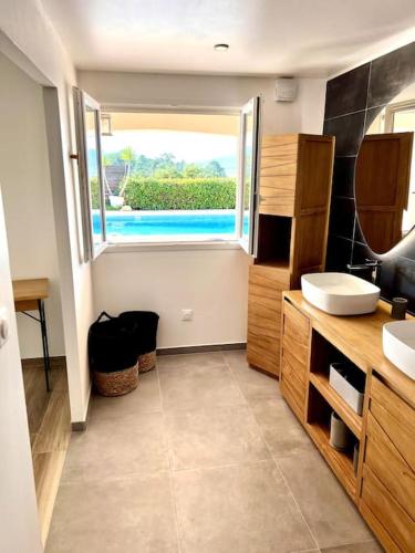 une salle de bain avec un lavabo et une grande fenêtre dans l'établissement Villa avec piscine et jacuzzi 3 min mer, à Grosseto-Prugna