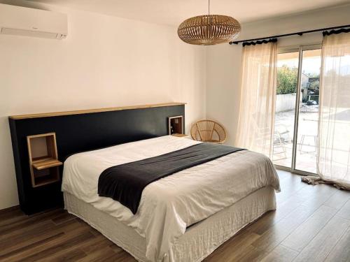 ein Schlafzimmer mit einem großen Bett und einem großen Fenster in der Unterkunft Villa avec piscine et jacuzzi 3 min mer in Grosseto-Prugna