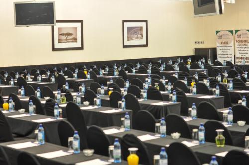 a conference room with tables and chairs and a screen at Safari Hotel & Convention Centre in Rustenburg