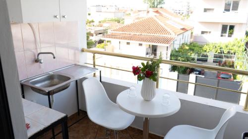 una mesa blanca con un jarrón de flores en el balcón en Villa Osmani en Durrës