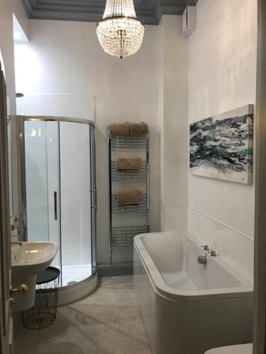 a bathroom with a tub and a sink and a chandelier at Silversprings - City Centre Apartments with Parking in Exeter
