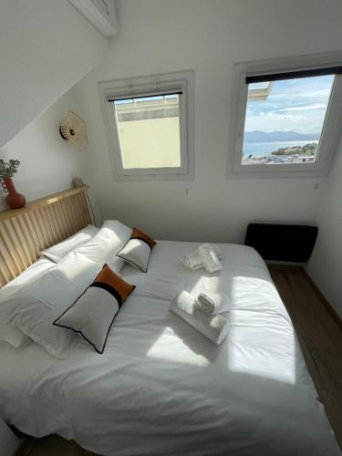 - un grand lit blanc dans une chambre avec 2 fenêtres dans l'établissement Duplex en bord de mer avec piscine et parking, à Cannes