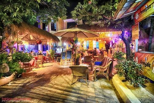 un restaurant avec des chaises, des tables et un parasol dans l'établissement Tiki garden, à Kampot