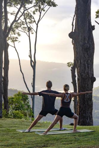 a man and a woman doing yoga in a field at Verandah House Country Estate in Mount Tamborine