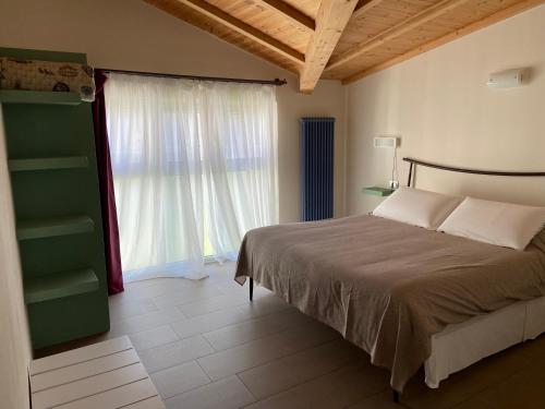 a bedroom with a bed and a large window at Affittacamere Casamatta in La Morra