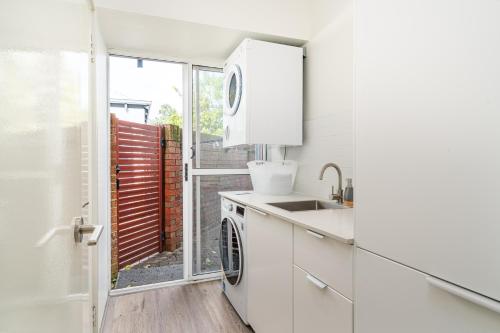 Abbys Beach Villa في Broadwater: مطبخ أبيض مع حوض وغسالة أطباق