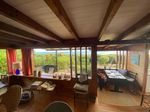 a living room with a table and chairs and windows at Cozy Summer House In The First Row To The Water, in Hornbæk