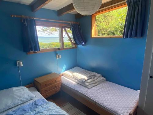 1 Schlafzimmer mit 2 Einzelbetten und einem Fenster in der Unterkunft Cozy Summer House In The First Row To The Water, in Hornbæk