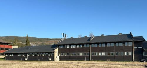 um grande edifício castanho com um telhado preto em Karivollen Overnatting em Melhus