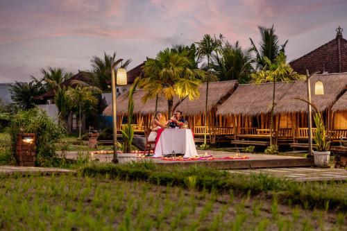 a bride and groom sitting at a table in front of a resort at Candy Villa by Pramana Villas in Ubud