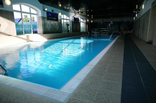 een groot zwembad met blauw water in een gebouw bij Hotel Kalchem in Brzozie