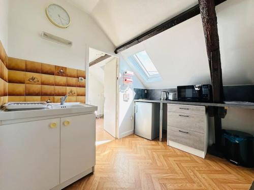 une cuisine avec un évier et une horloge murale dans l'établissement Morgan' Appartement, à Laon