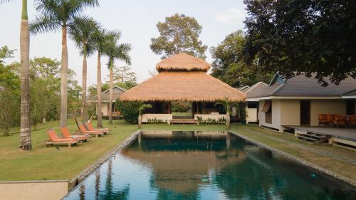 a swimming pool with chairs and a thatch roof at Khla Lodge in Kampot