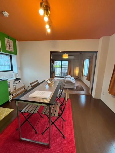 a dining room with a table and a red rug at 777 Takamatsu Guest House in Takamatsu