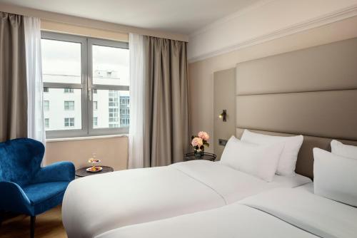 a hotel room with a bed and a blue chair at NH Berlin Kurfürstendamm in Berlin