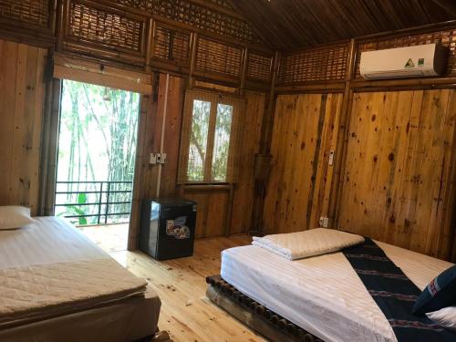 a room with two beds and a television in it at Bamboo Eco Lodge - Venuestay in Mai Chau