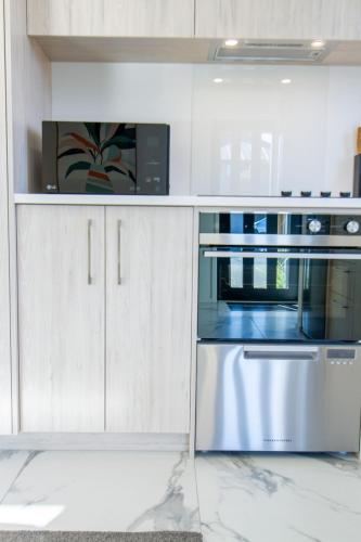 a kitchen with a stainless steel oven and a microwave at Gateway to Hagley park - 2 bed w/carpark in Christchurch