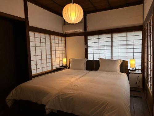 un grande letto bianco in una stanza con finestre di 昭和レトロが息づく狐白庵 a Nagano