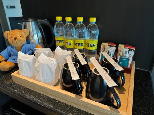 a wooden tray with bottles of water and a teddy bear at Golden Tulip Mandison Suites in Bangkok