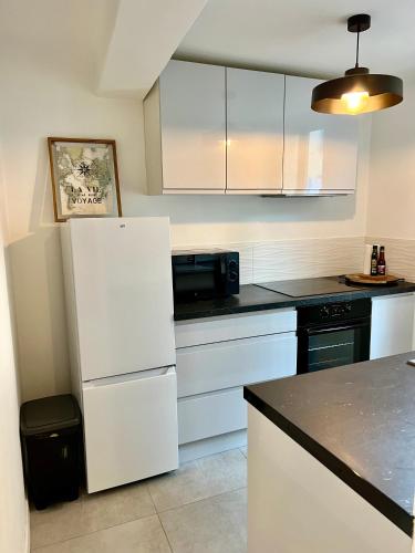 une cuisine avec des armoires blanches et un réfrigérateur blanc dans l'établissement Charmant 2P cœur de ville et plage, à Sainte-Maxime