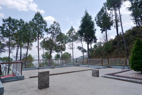 a patio with a fence and trees in the background at HIM VIEW RETREAT in Rānīkhet