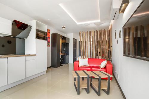 un salon avec un canapé rouge et une table dans l'établissement Bambou Heliopolis, au Cap d'Agde