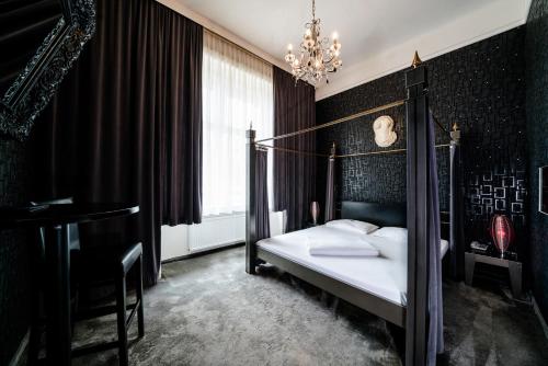 a bedroom with a canopy bed and a chandelier at Hotel Goldene Spinne in Vienna