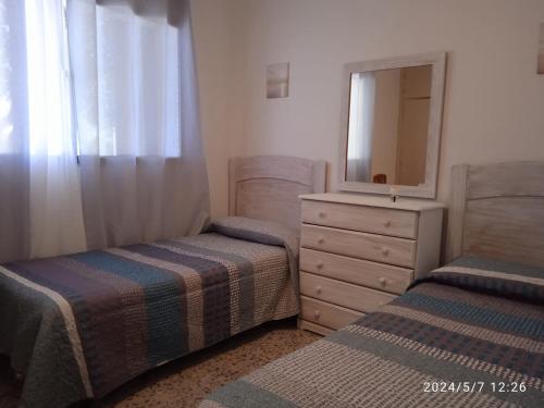 a bedroom with two beds and a dresser with a mirror at Apartamento Caños de Meca in Los Caños de Meca
