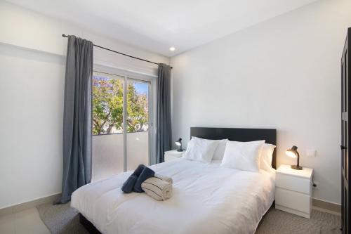 a bedroom with a large white bed with a window at Skipper House in Loulé